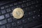 Golden bitcoin coin on black qwerty desktop keyboard