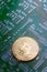 Golden bitcoin on green board with microchips and microcircuits on background.