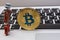 Golden bitcoin stand on silver notebook keyboard