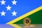 Golden bitcoin stands on a background of state flag of Solomon Islands