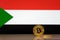Golden bitcoin stands on a background of state flag of Sudan