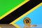 Golden bitcoin stands on a background of state flag of Tanzania