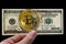 Golden bitcoin and us dollars in hand. The coin is crumbling. The concept of cryptocurrency in the market crisis. Black background