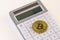 Golden bitcoin on white calculator and cream table