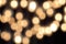 Golden bokeh on a black background, abstract dark backdrop with defocused warm lights