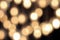 Golden bokeh on a black background, abstract dark backdrop with defocused warm lights