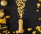 Golden bottle of champagne spills out gold sparkles in frame of gold festive Christmas decor confetti balls gifts on black