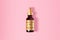 Golden bottle of a hyaluronic acid serum resting on a pastel pink surface