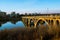 A Golden Bridge Reflecting In the River Glass-Like Surface At Sunset