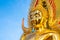 golden Buddha face and the Buddhist yellow flag in outdoor of the temple in Thailand with the blue sky copy space