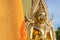 golden Buddha face and the Buddhist yellow flag in outdoor of the temple in Thailand with the blue sky copy space