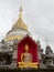 Golden Buddha image in red arch over main stupa or pagoda and sky background in Buppharam temple, Chiang Mai, Thailand