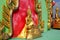 Golden Buddha statue side view with red-green background at Wat Saman Rattanaram