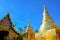 Golden Buddhist temple, shiny golden pagoda and wooden church at Wat Pra Sing with blue sky background, Chiang-mai province