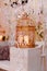 Golden cage with candles on a white wooden pedestal. Wedding photo zone