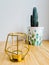 Golden candlestick next to a cactus in a pot stand on a wooden table