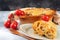 Golden canelonni with meat, tomatoes, cheese sauce and pasta in alternating layers on a rustic plate