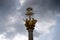 Golden Christian cross with a halo above and sculptures of angels on a cloudy sky