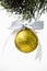 Golden Christmas ball hanging on pines tree leaf on white