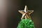 Golden Christmas star ball on ornament pine Christmas treetop closeup on dark background