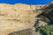 Golden cliffs in California with visible geologic striations and desert plants