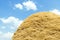 Golden color straw haystack on field and blue sky with clouds