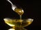 A golden colored olive oil being poured from a spoon isolated on the background. Generative AI