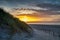 Golden colors of the sunset behind a sand dune. a sign on the dune with text, forbidden access