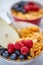 Golden cornflakes with fresh fruits of raspberries, blueberries and pear in ceramic bowl