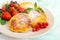 Golden cottage cheese pancakes with fresh berries on a plate on white wooden background.