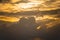 golden coudy sky with towering clouds, sun hidden behind it with the orange glow of sunrise sunset shot in andaman