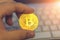 Golden cryptocurrency bitcoin in man hand on keyboard background