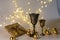 Golden cups, golden glass balls and various Christmas decorations, illuminated background of a chain of white lights