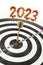 Golden dart in the middle of black and white concentric circles target, with 2023 number on top