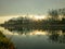 Golden Dawn Reflections on a Calm Riverside with Flying Birds