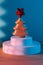 Golden decorative Christmas tree with a red shining star on a white podium with a fan on a blue background, New Year