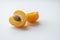 Golden Delights: Half Apricot with Pip in Nature\'s Embrace. set against an elegant off-white background