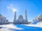 Golden-domed mosque with twin minarets against a clear blue sky. Sunlight Glistening on White Marble Mosque Minarets