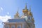 Golden domes and decoration of Peterhof Grand Palace against the bright sky