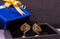 Golden earring studed with red stone in brown box on black background with a blue giftbox. Earing gift concept