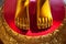 Golden feet on a red background vivid close-up. Asian shrine sculpture