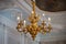 Golden figured chandelier with electric candles on ceiling with stucco and painting in the Gatchina Palace