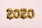Golden foil balloons on pink pastel background. Inflatable numbers 2020. Christmas concept