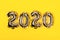 Golden foil balloons on yellow background. Inflatable numbers 2020. Christmas concept