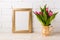 Golden frame mockup with magenta pink tulips in golden vase