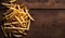 Golden French Fries Piled on Rustic Wooden Table, Copy Space