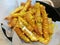 Golden French fries serving in the paper basket top with melt cheddar cheese with blur background, stylist food, fusion food, Clos