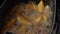 Golden fried potato wedges frying in hot boiling oil.