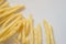 Golden fries on white background. Yellow french fries with wooden sauce cup on plain floor