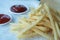 Golden fries on white background. Yellow french fries with wooden sauce cup on plain floor. Copy space